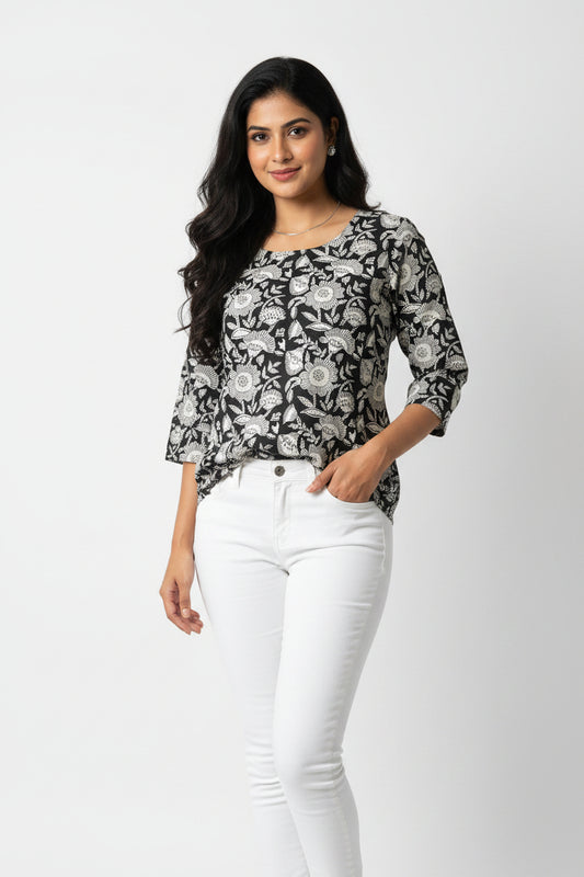 A long-sleeved batik shirt with a black and white floral pattern, laid flat on a bright green background.