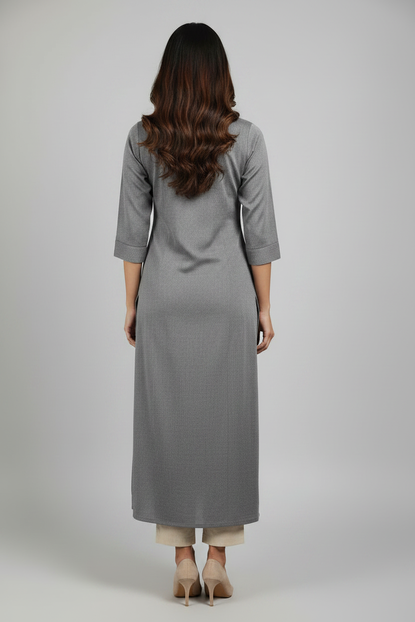 A woman modeling a long, straight-fit gray kurta dress with three-quarter sleeves and a side slit, paired with beige heels, against a solid light gray studio background.