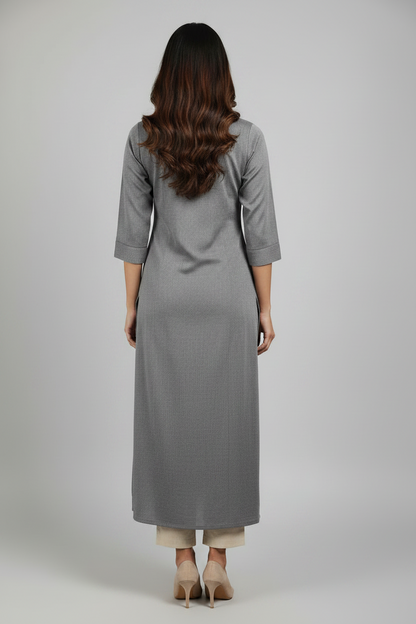 A woman modeling a long, straight-fit gray kurta dress with three-quarter sleeves and a side slit, paired with beige heels, against a solid light gray studio background.