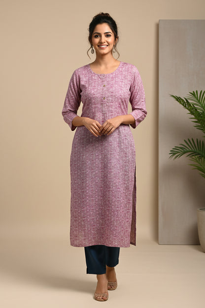 A long-sleeve pink and white patterned tunic top laid flat on a bright green sheet.
