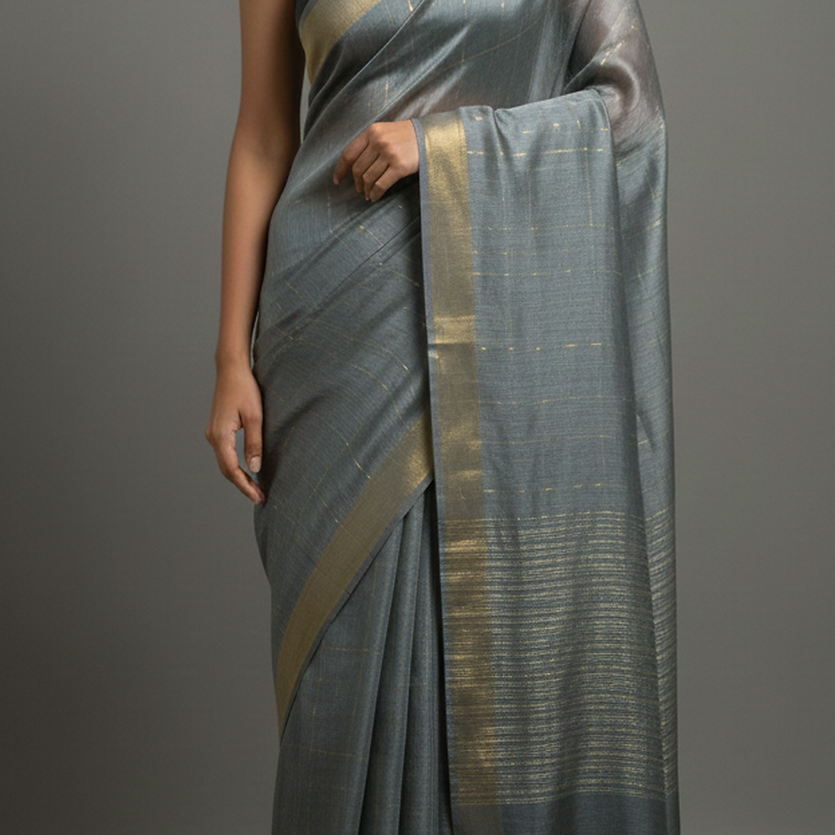 Gray saree with gold border draped over a person on a gray background
